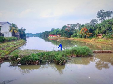 Ortasında yemyeşil ağaçlarla dolu gölün atmosferi ve bulutlu gökyüzünün gölgesini yansıtan sakin suyu Endonezya 'nın Bogor kentinin eteklerinde yer almaktadır..