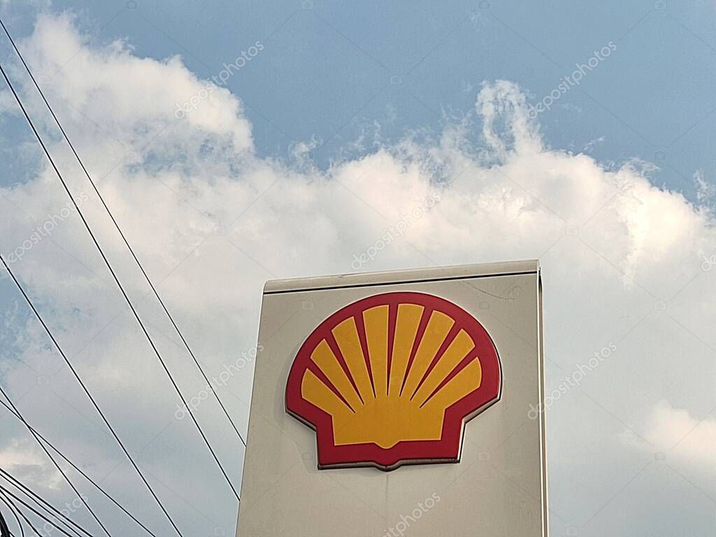 Bogor, Indonesia - July 18, 2025: The iconic Shell logo, with its red and yellow scallop shell design, is displayed at a gas station. A cloudy blue sky and cables are visible in the background