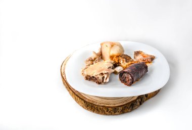 Beyaz bir tabakta, ahşap bir masa örtüsünde pişmiş bezelyeler..