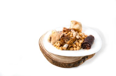 Beyaz bir tabakta, ahşap bir masa örtüsünde pişmiş bezelyeler..