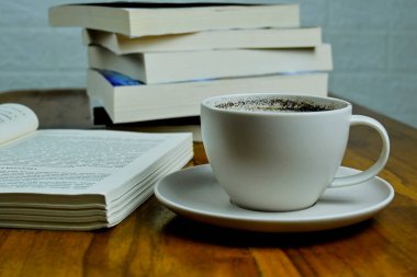 Siyah arkaplanı olan bir fincan kahve ve kitap.