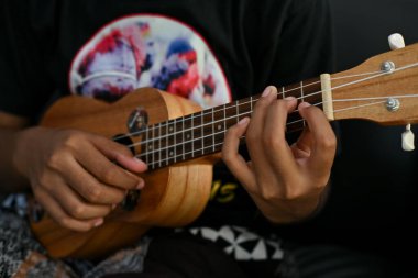 Genç Asyalı kadın oturma odasında ukulele oynuyor, kapat.