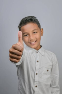 Asyalı genç bir Endonezyalı 'nın mutlu bir şekilde başparmak kaldırışı portresi.