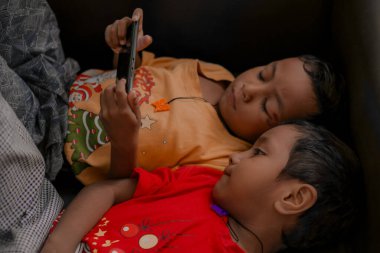 Akıllı telefonda oyun oynayan Asyalı ikiz çocuklar