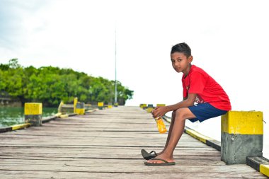 İskelede oturan küçük bir çocuğun portresi.