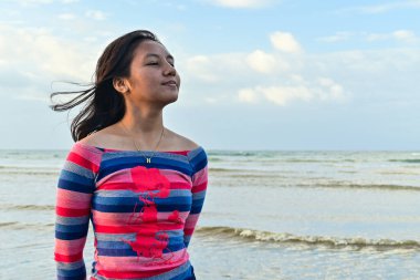 Sahilde sıradan giyinmiş Asyalı bir kadın.