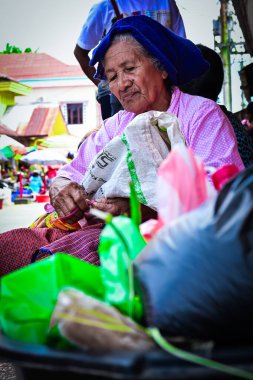 Ambon, Endonezya - 24 Mart 2020: Endonezya 'nın Maluku bölgesinde tipik giyinmiş yaşlı bir kadın yol kenarında satış yapıyor