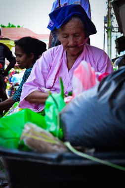 Ambon, Endonezya - 24 Mart 2020: Endonezya 'nın Maluku bölgesinde tipik giyinmiş yaşlı bir kadın yol kenarında satış yapıyor