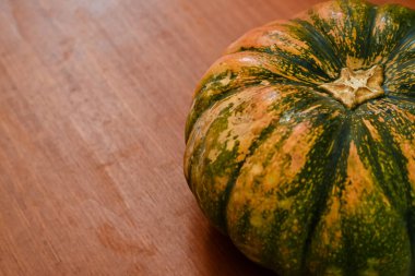 Tahta bir yüzeyde yeşil ve sarı bir kabak.