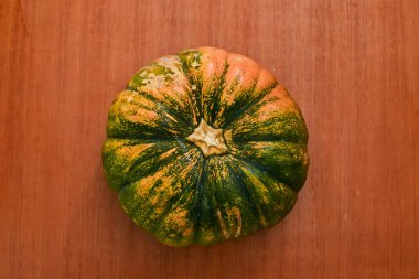 Tahta bir yüzeyde yeşil ve sarı bir kabak.