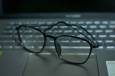 Dizüstü bilgisayarda duran bir çift gözlük.
