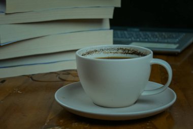 Bir fincan kahve ve kitap masanın üstünde.