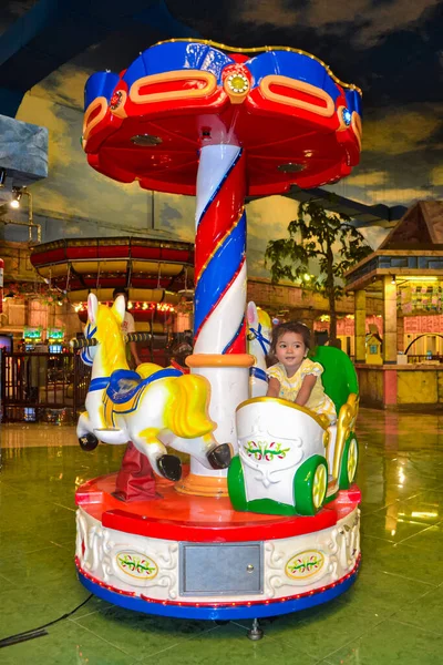 Ambon, Endonezya - 12 Nisan 2013: Alışveriş merkezinde atlıkarıncaya binen bir çocuk