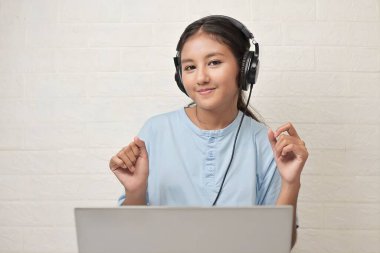 Bir kız dizüstü bilgisayarda müzik dinlemek için kulaklık takıyor.