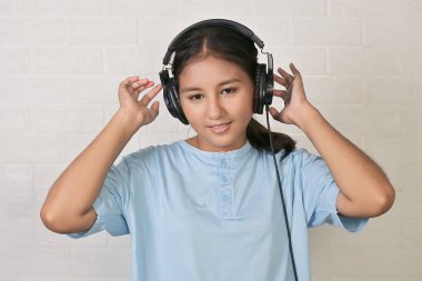 Bir kız müzik dinlemek için kulaklık takıyor.