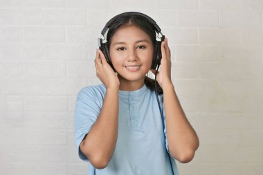 Bir kız müzik dinlemek için kulaklık takıyor.