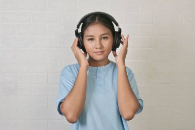 Bir kız müzik dinlemek için kulaklık takıyor.