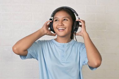 Bir kız müzik dinlemek için kulaklık takıyor.