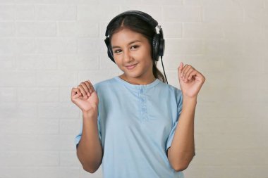 Bir kız müzik dinlemek için kulaklık takıyor.