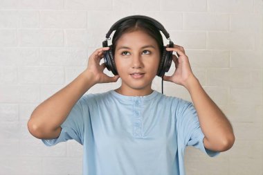 Bir kız müzik dinlemek için kulaklık takıyor.