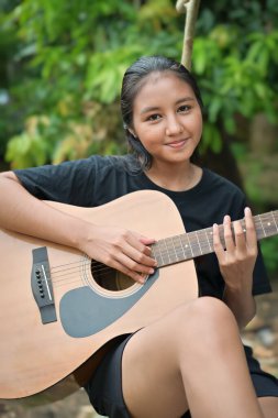 Parkta gitar çalan mutlu kız.