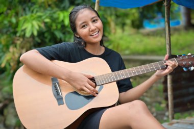 Parkta gitar çalan mutlu kız.