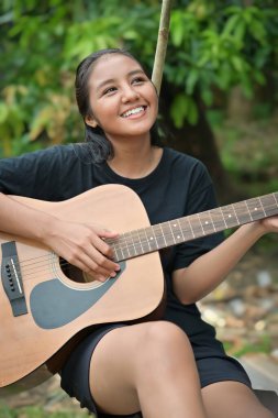 Parkta gitar çalan mutlu kız.