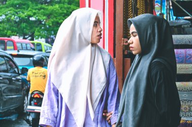 Ambon, Indonesia - April 4, 2024: Two Muslim women are standing in the window of a shop clipart