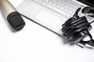 Beyaz arka planda stüdyo kulaklıkları ve dizüstü bilgisayarı olan stüdyo mikrofonu.