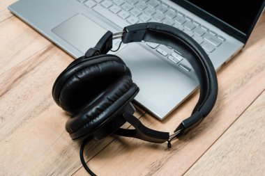 Kulaklıklar ve dizüstü bilgisayar ahşap masada.