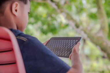 Bir çocuk elinde tablet tutuyor.