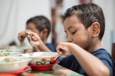 Endonezyalı çocuk bir kase köfte yiyor.