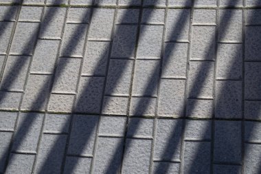 Çubukların gölgesine sahip kaldırım ve asfalt arkaplan.