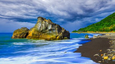 Two big stone with salt and clear texture in the sea ,silky wave and much cobblestone in arc-shaped beach,cloudy sky,Scenic scene. Pingtung Couty, Taiwan.For branding,calender,postcard,screensave,poster,cover,website.High quality photo