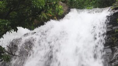 Ormandaki şelalenin üst su çıkışındaki dalgalara yakın çekim. Şok edici akan su, güçlü çarpışma manzaralı bir sahne oluşturur. Laiyi, Kaohsiung Şehri, Taiwan4K Gerçek zamanlı Düşük açılı yüksek kaliteli video