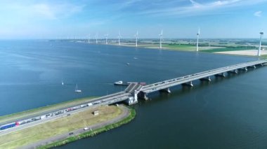 Flevoland, Hollanda 'da bir köprünün altından geçen kargo gemisi, 4K İHA görüntüsü