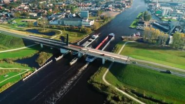 Friesland, Hollanda 4K insansız hava aracı görüntüleriyle aynı anda iki kargo gemisi bir köprünün altından geçiyor.