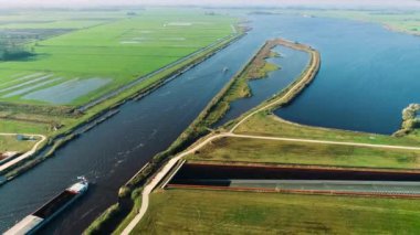 Huzurlu Hollanda Düz Peyzajı 'nda Su kemerini geçen Kargo Gemisinin Uzun Vuruşu - Friesland, Hollanda 4K Drone Görüntüsü