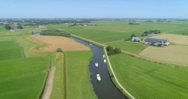 Bendy River 'daki eğlence tekneleri ve Hollanda Düzlüklerinde Bisikletçiler - Friesland, Hollanda, 4K Drone Görüntüleri