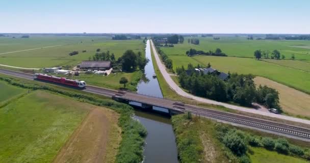 Червоно Білий Поїзд Перетинає Невеликий Міст Через Канал Кінематографічний Знімок — стокове відео