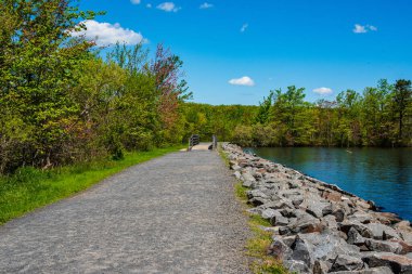 New Jersey, ABD 'deki Manasquan Nehir Parkı' nda köprüsü olan bir yürüyüş yolunun fotoğrafı.