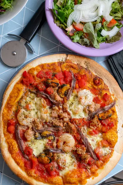 Deniz ürünleri ve salatalı pizza.