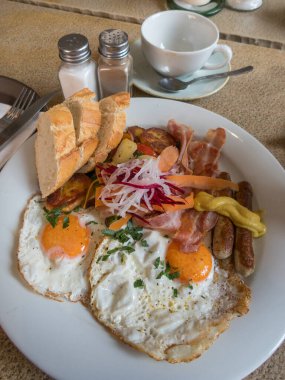 Kızarmış yumurta, sebze, domuz pastırması ve sosisle kahvaltı.