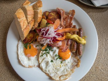 Kızarmış yumurta, sebze, domuz pastırması ve sosisle kahvaltı.