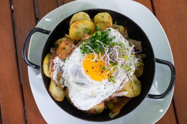 Patates yahnili metal güveç ve kızarmış yumurta.