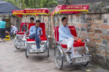 Hanoi, Vietnam - 10 Nisan 2025: Üç tekerlekli bisiklet sürücüleri şehir merkezinde mola veriyor