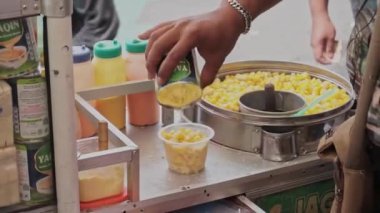 Jasuke (Jagung Susu Keju), sütle ve rendelenmiş peynirle karıştırılmış geleneksel bir Endonezya mezesidir. Satıcı jasuke 'yi alıcıya veriyor..