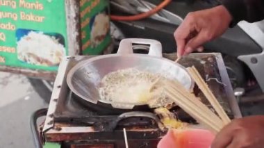 Telur Gulung 'un kızartma işlemi. Telur Gulung, çubukta kızartılmış yumurta ve pirinç eriştesinden yapılmış geleneksel Endonezya sokak yiyeceğidir..