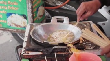 Telur Gulung 'un kızartma işlemi. Telur Gulung, çubukta kızartılmış yumurta ve pirinç eriştesinden yapılmış geleneksel Endonezya sokak yiyeceğidir..