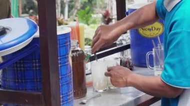 Es Kelapa Muda ya da genç hindistan cevizi buzu, popüler bir Endonezya içkisi. Satıcı alıcıya genç hindistan cevizi buzu servis ediyor..